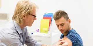 Doctor and patient in doctors office preparing patients arm