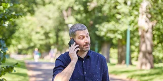 Man on phone walking dog in park