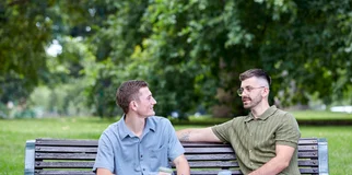 Friends on park bench having coffee