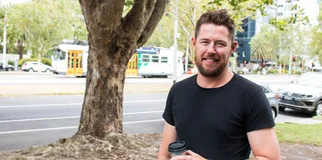 Man smiles at camera holding coffee photo