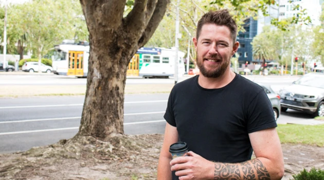 Man smiles at camera holding coffee photo